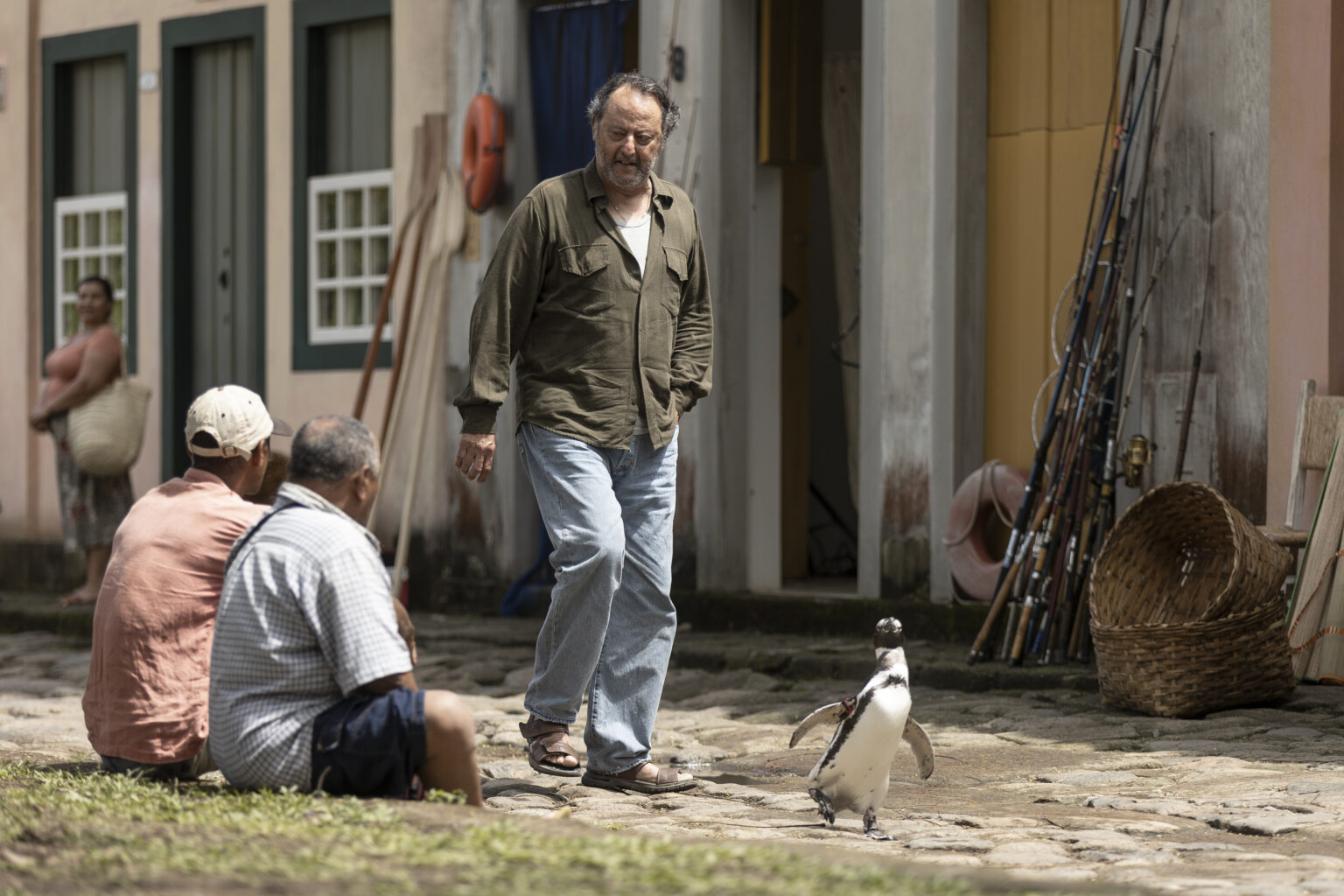 PARATY, SP, BRASIL, 05-10-2022: Dindim is back to the village and all villagers gather and take pictures. Dindim, a young Magellanic penguin, returns to the sea in search of food after the mating season in Patagonia.
After managing to escape the persecution of predators, the dangers of fishing nets, plastics and oil spills that pollute the oceans, he loses his way and ends up on the Brazilian coast very weakened.
With his body covered in oil and badly injured, Dindim is saved by João, an old fisherman who lives in Ilha Grande. An unlikely friendship is born between a man and a penguin who, together, will discover the value of love, family and hope for a better future.
The live-action film will have the narrative told from the point of view of our penguin, Dindim, who reflects, draws conclusions and expresses his affection for the one who saved his life. This gripping story tells of life and death, brotherhood and friendship, and ultimately, how we are all connected as living creatures.
Connected by something bigger than us. (Foto: Adriano Vizoni/Pivô Audiovisual), Showrunner: ; Direção: David Schürmann | DIVULGAÇÃO.